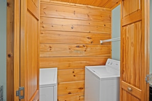 A laundry room with wooden walls and two white washing machines. - Serenity- Find your solitude at the 1 bedroom cabin! (Gatlinburg)