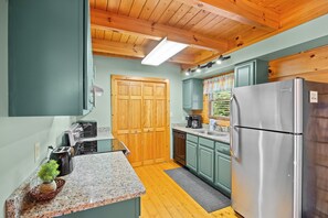 Cocina compacta con armarios de madera, refrigerador de acero inoxidable y horno empotrado.