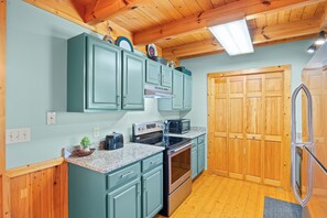 A kitchen with teal cabinets, a stainless steel stove, and a wooden door. - Serenity- Find your solitude at the 1 bedroom cabin! (Gatlinburg)