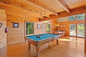 Interior de madera con mesa de billar, cuadros enmarcados y extintor.