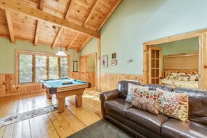 Relax in a spacious room with a pool table, comfortable sofa, and large windows.