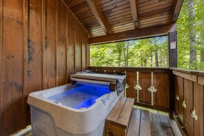 Een houten chalet met een jacuzzi en een bankje.