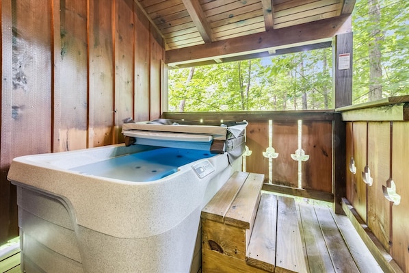 Relax in a serene cabin with a spa bath and massage table, overlooking a forest view.