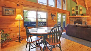 A wooden interior with a dining table, chairs, a sofa, and a fireplace.
