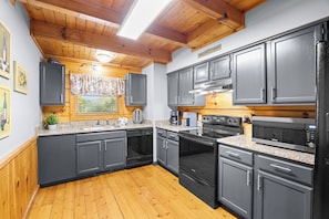 A modern kitchen with grey cabinets, a stainless steel range, and a wooden floor.