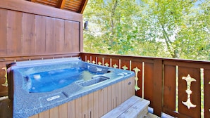 A hot tub on a wooden deck with a view of trees.