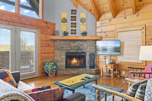 A cozy living room with a fireplace, wooden walls, and a television.