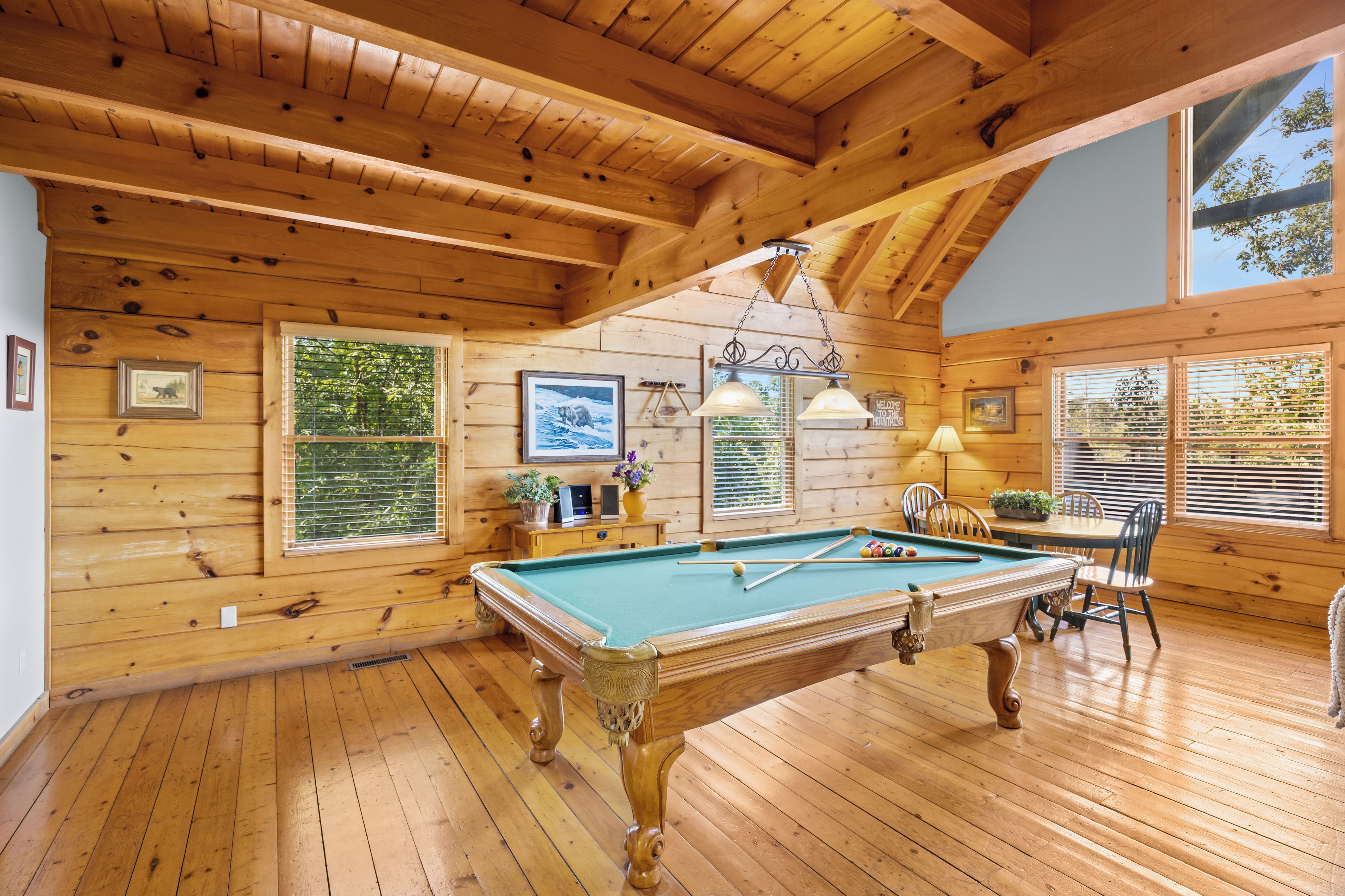 Un intérieur en bois agrémenté d’une table de billard, de tableaux encadrés et d’une enseigne accueillante.