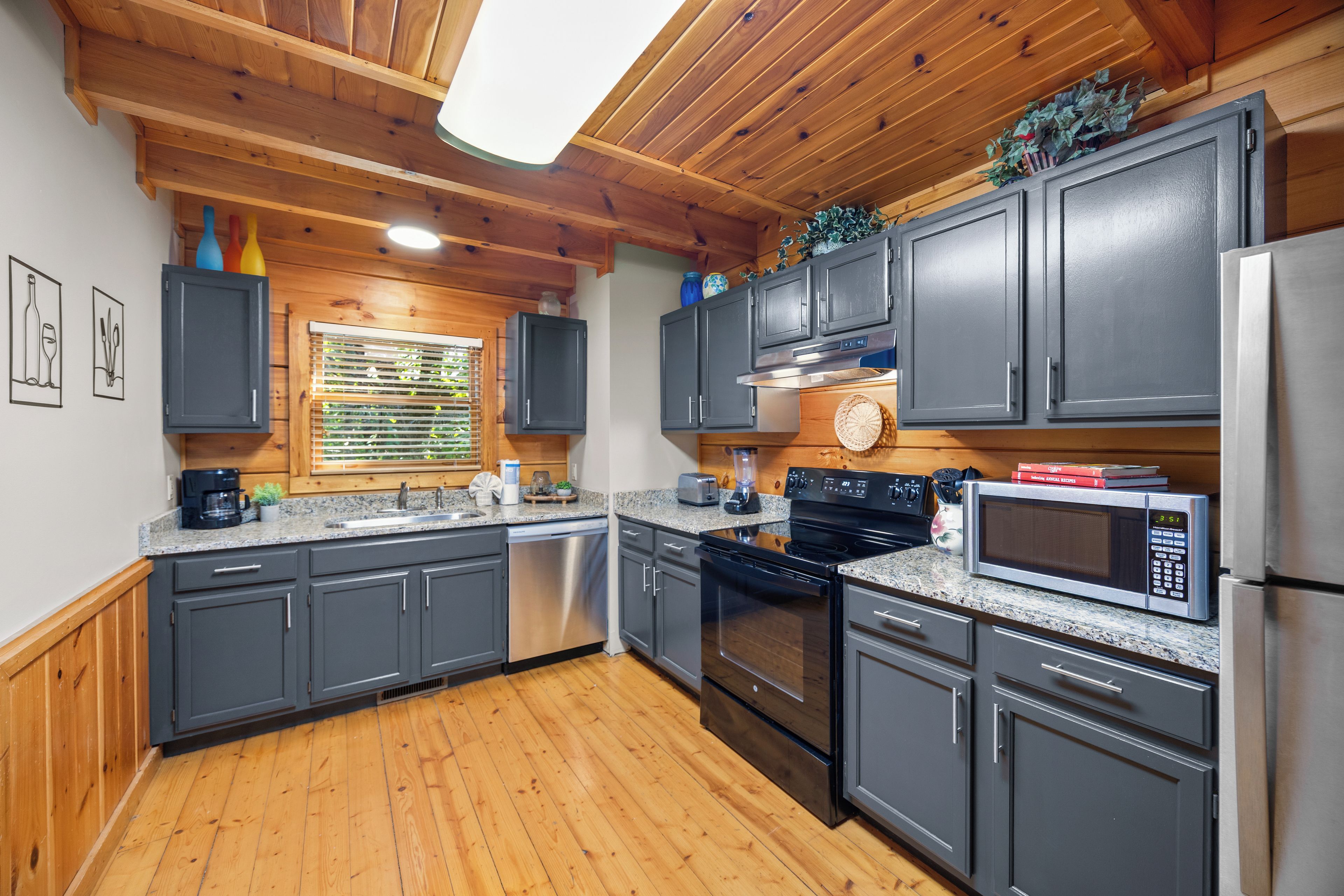 Una cucina moderna con mobili antracite, elettrodomestici in acciaio inossidabile e soffitto in legno.
