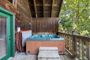 Een houten terras met een jacuzzi, een deur met raam en een bord.