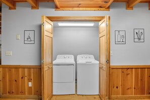 Une buanderie avec deux machines à laver blanches, des murs en bois et un plafond avec des poutres apparentes.
