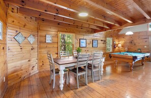 Un interior de madera con mesa de billar, mesa de comedor y sillas.