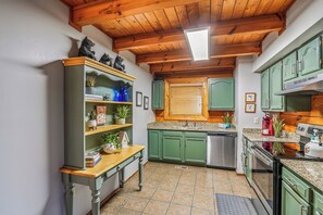 A kitchen with green cabinets, a wooden table, and a built-in oven. - Three Bears-  Enjoy a panoramic view of the Cove Mountain range! 2 bed/2 bath cabin! (Gatlinburg)