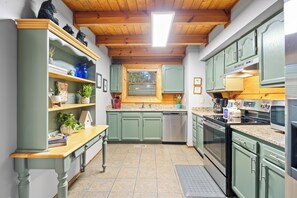 A kitchen with green cabinets, a wooden countertop, and a built-in oven. - Three Bears-  Enjoy a panoramic view of the Cove Mountain range! 2 bed/2 bath cabin! (Gatlinburg)
