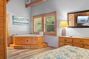 A room with a wooden bathtub, a painting, a window with blinds, a lamp, and a television. - Three Bears-  Enjoy a panoramic view of the Cove Mountain range! 2 bed/2 bath cabin! (Gatlinburg)