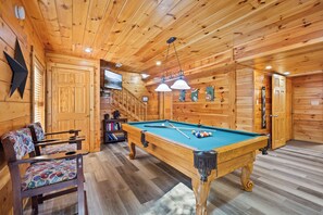 Un intérieur en bois avec une table de billard, des chaises et un escalier.