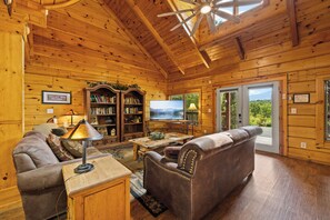 A cozy wooden interior with a sofa, a television, and a bookshelf.