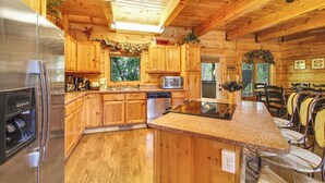 A wooden cabin kitchen with a stainless steel refrigerator, microwave, and dishwasher.