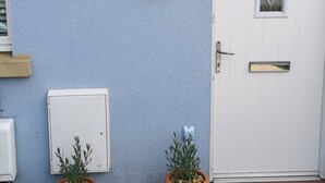 A house with a blue exterior, a white door, a number '80' sign, a lantern, and a small potted plant. - The Little House, Boutique Home Near the sea (Chichester)