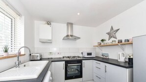 A modern kitchen with a sink, stove, oven, microwave, and a star decoration on the wall. - The Little House, Boutique Home Near the sea (Chichester)
