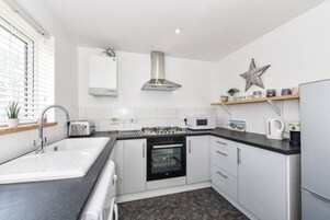 Cozinha moderna com pia, fogão, forno, micro-ondas e uma decoração em forma de estrela na parede.