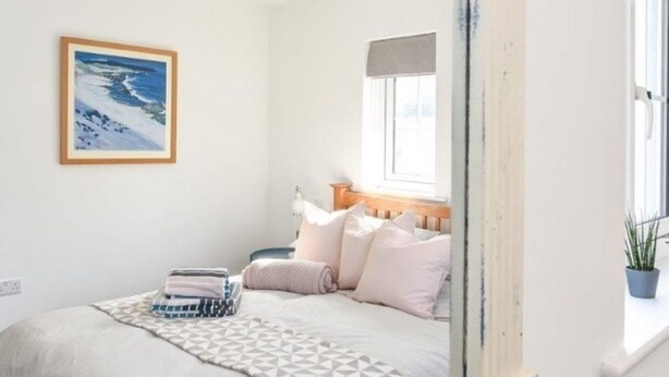 A bedroom with a bed, pillows, a blanket, a painting, and a window. - The Little House, Boutique Home Near the sea (Chichester)