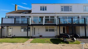 A two-story residential building with a garage, a covered porch, and a boat trailer. - No. 28 Contemporary Beach Side Property With sea Views (Chichester)