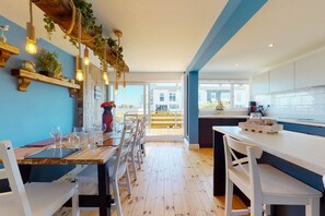 A modern kitchen with wooden countertops, white cabinets, and a dining area with a wooden table and chairs. - No. 28 Contemporary Beach Side Property With sea Views (Chichester)