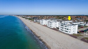 A coastal hotel with multiple white buildings, a sandy beach, and a clear blue sky. - No. 28 Contemporary Beach Side Property With sea Views (Chichester)