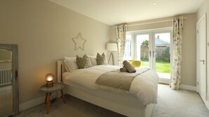 Quarto com cama, luminária de cabeceira e vista para o exterior.