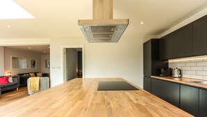 Uma cozinha moderna com bancada de madeira, armários pretos e uma ilha central.