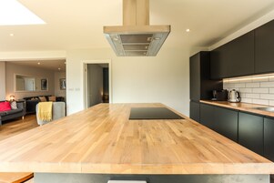 Uma cozinha moderna com bancada de madeira, armários pretos e uma ilha central.