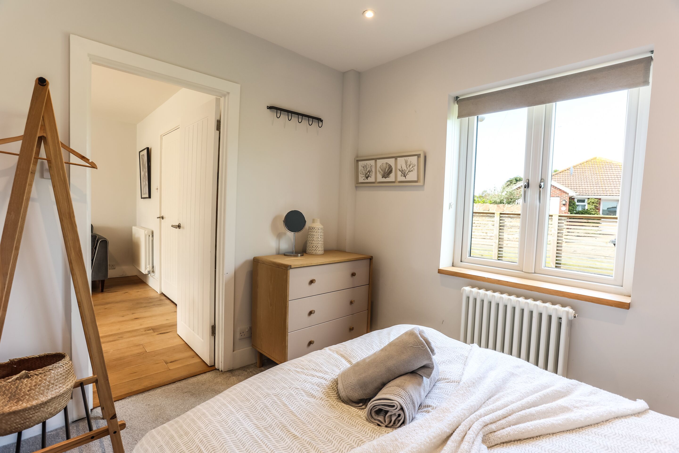 A bedroom with a bed, a dresser, a radiator, a window, and a door leading to another room.