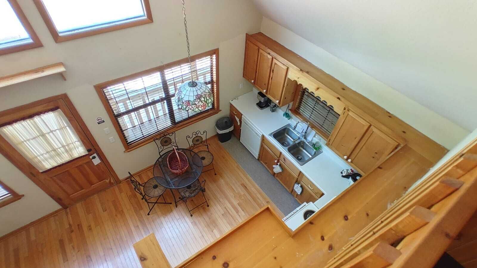 Una cocina con armarios de madera, una mesa de comedor con sillas y una ventana con persianas.