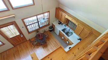 Una cocina con armarios de madera, una mesa de comedor con sillas y una ventana con persianas.