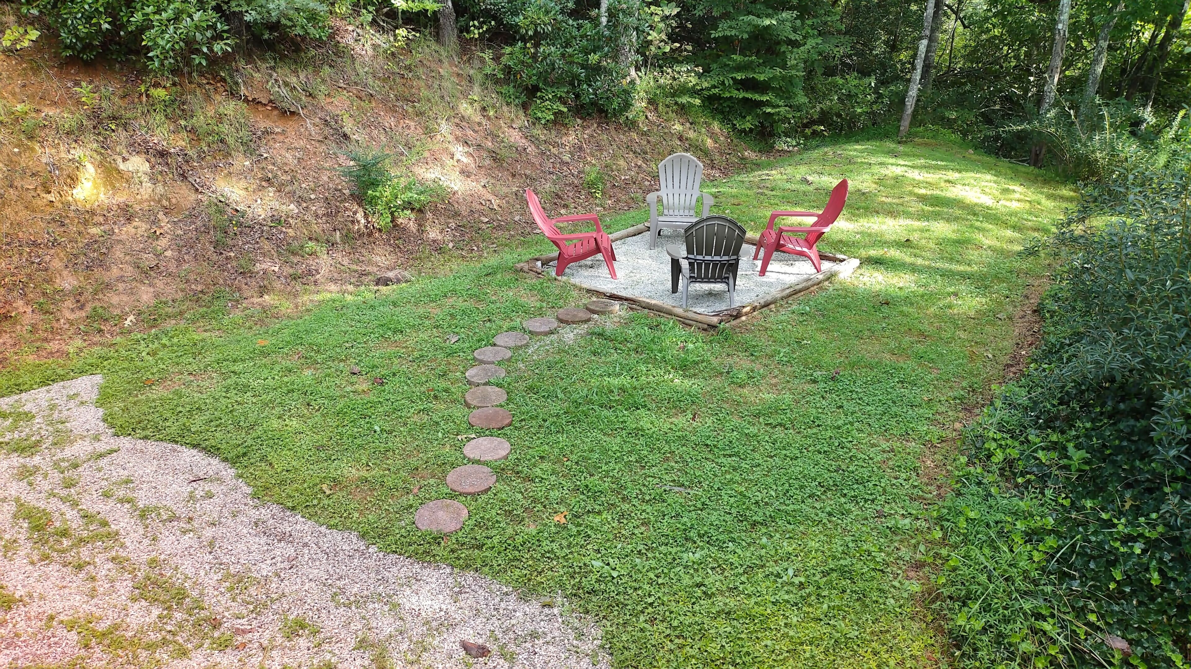 A patio with a gravel path leading to a seating area with chairs and a table.