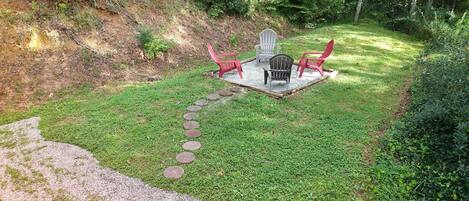 A patio with a gravel path leading to a seating area with chairs and a table.