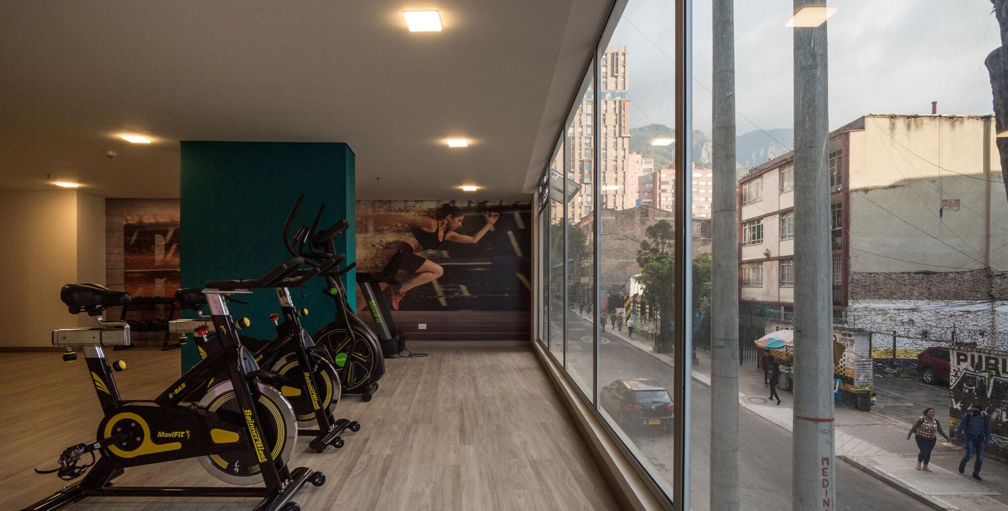 A gym with stationary bikes and a large window overlooking a street.