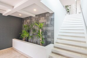 A modern interior with a stone wall, a white reception desk, and a staircase.