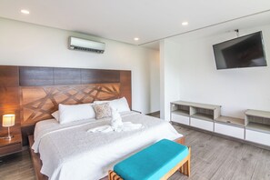 Ein modernes Hotelzimmer mit einem großen Bett, einem Flachbildfernseher an der Wand und integrierten Stauraumeinheiten.