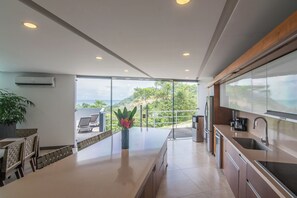Eine moderne Küche mit einer großen Kochinsel, integrierten Geräten und Blick auf eine üppige Landschaft.