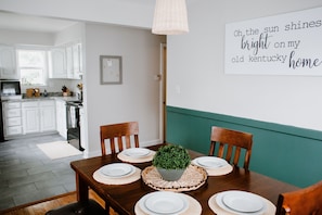 A dining area with a table set for four, a decorative plant centerpiece, and a wall with a motivational quote.