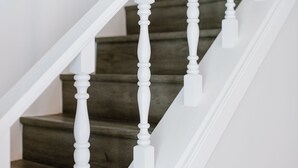 Eine Treppe mit weißen Balustern und dunklen Holzstufen.