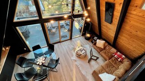 A cozy cabin interior with a dining area, a fireplace, and large windows offering a view of the outdoors. - Modern A-Frame Cabin in Mammoth (Mammoth Lakes)