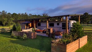 A mobile home with a covered patio, a hammock, and a small garden area.