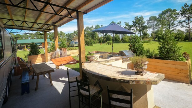 A covered outdoor patio with a bar area, seating, and a hammock.