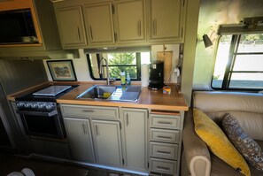 Una kitchenette funcional con estufa, lavamanos y armarios.