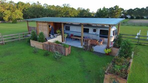 Una casa móvil con un porche cubierto, mobiliario exterior y un patio cercado.