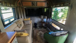 A cozy RV interior with a sofa, a green armchair, and a small table.