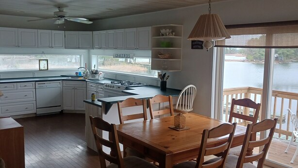 Una cocina con armarios blancos, una mesa de comedor de madera y vistas a un lago a través de amplios ventanales.